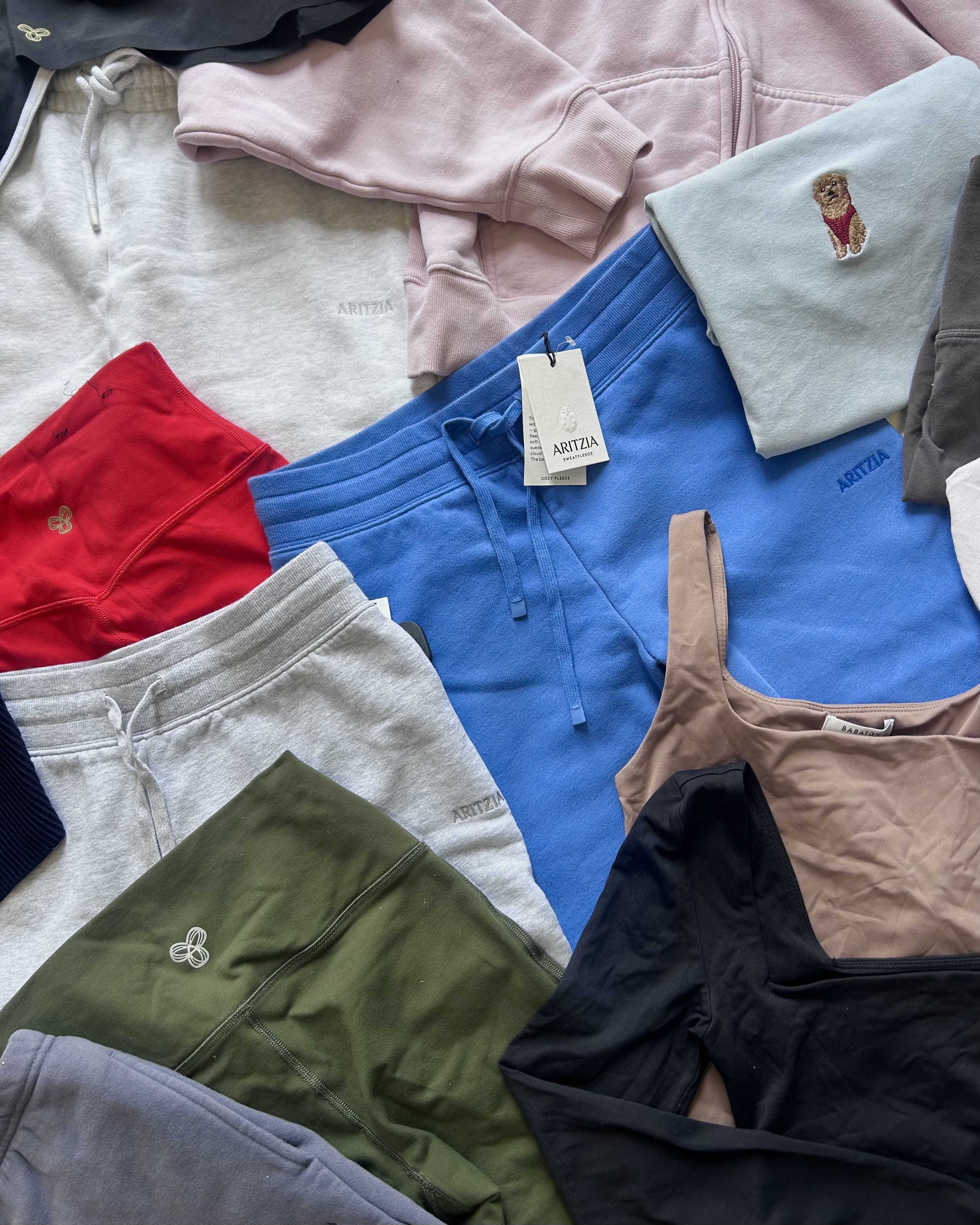 flatlay pile of clothing brands like aritzia, and skims